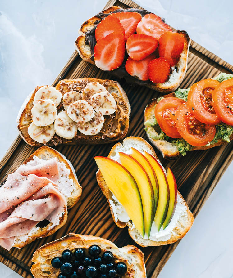 Delicious healthy toasts mix for breakfast, lunch or snack on a wooden board, top view 